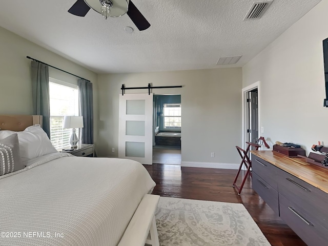 bedroom with dark wood-style floors, a barn door, multiple windows, and baseboards