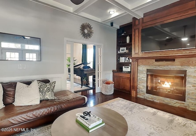 living room featuring built in features, dark wood finished floors, a tiled fireplace, and wainscoting