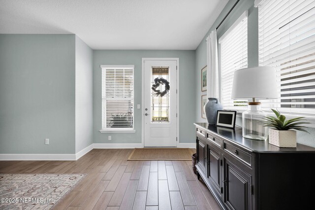 entrance foyer with baseboards and light wood-style floors