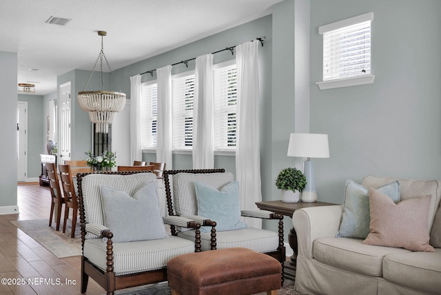 interior space featuring visible vents, plenty of natural light, wood finished floors, and a chandelier