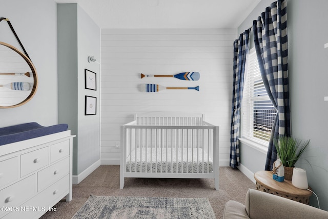 carpeted bedroom featuring baseboards, a nursery area, and wooden walls