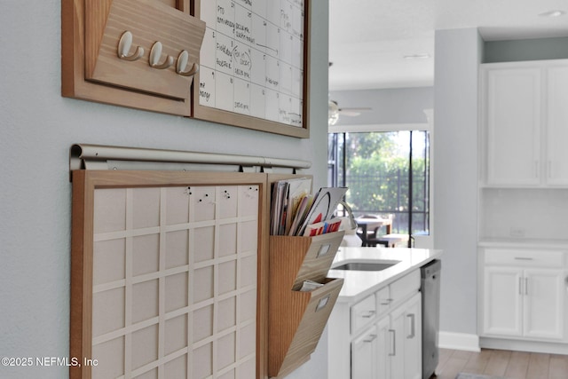 kitchen featuring dishwasher, white cabinetry, light countertops, and light wood-style floors