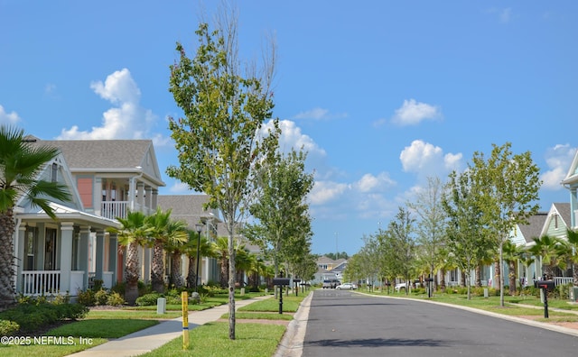 view of street featuring sidewalks, a residential view, curbs, and street lights