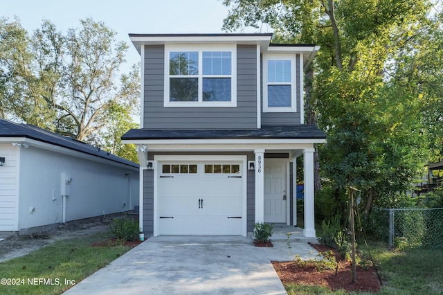 traditional-style house featuring an attached garage, fence, and concrete driveway