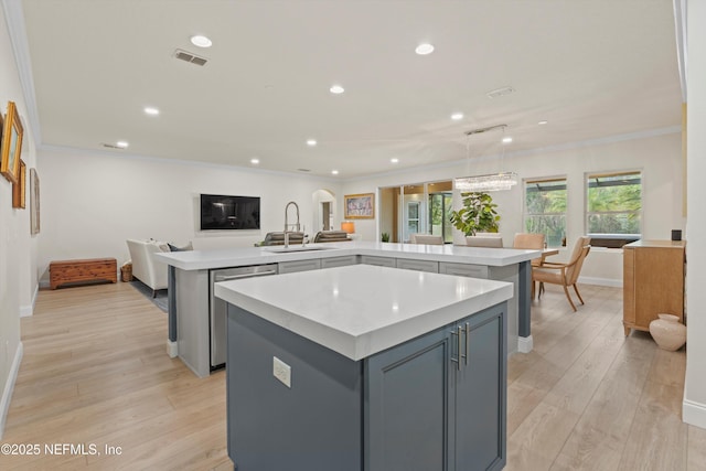 kitchen featuring visible vents, open floor plan, a center island, light countertops, and stainless steel dishwasher