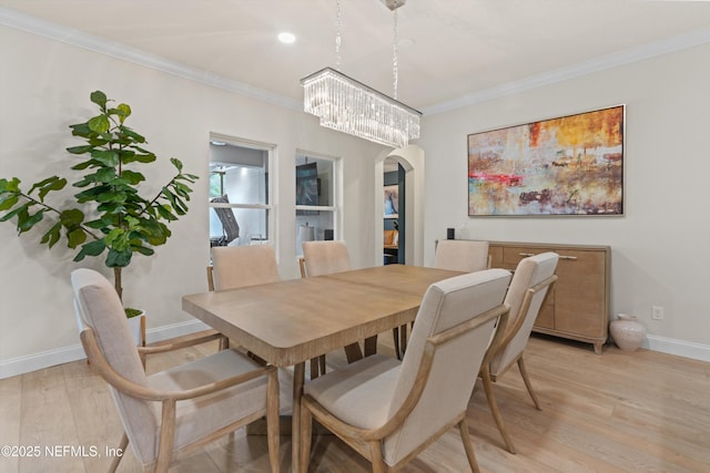 dining area featuring ornamental molding, arched walkways, and light wood finished floors