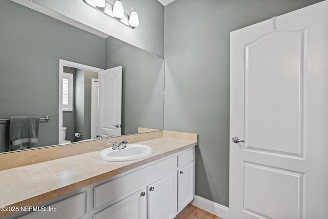 bathroom with vanity, toilet, and baseboards