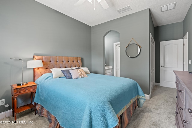 bedroom with light colored carpet, arched walkways, visible vents, and baseboards