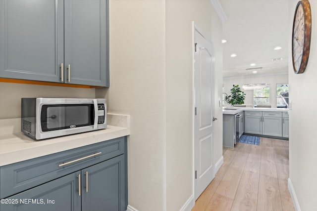 interior space with crown molding, light wood finished floors, recessed lighting, appliances with stainless steel finishes, and baseboards