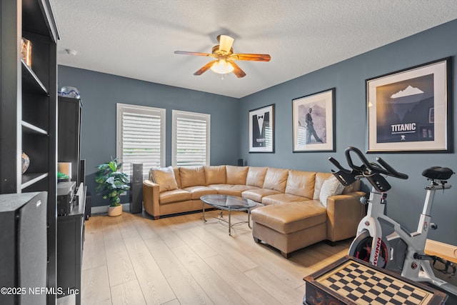 living room with baseboards, ceiling fan, a textured ceiling, and light wood finished floors