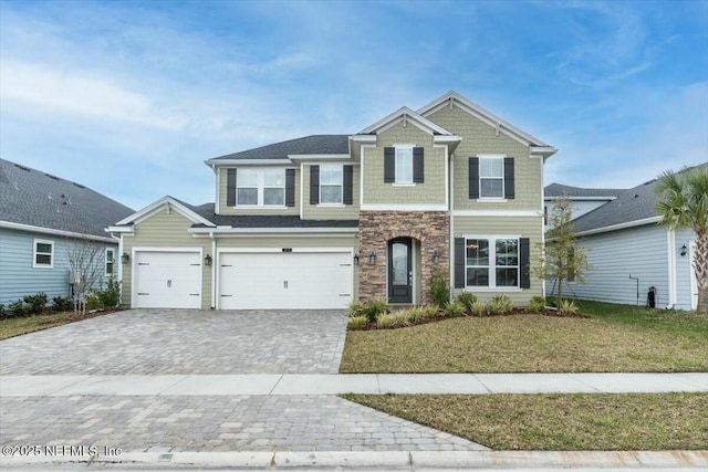 craftsman house featuring a garage, stone siding, a front lawn, and decorative driveway