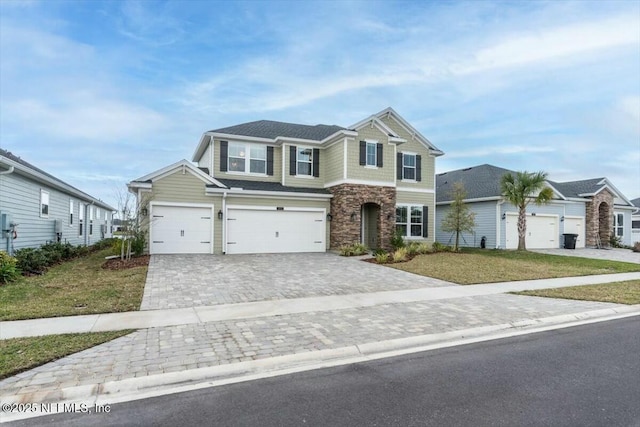 view of front of house featuring an attached garage, stone siding, a front lawn, and decorative driveway