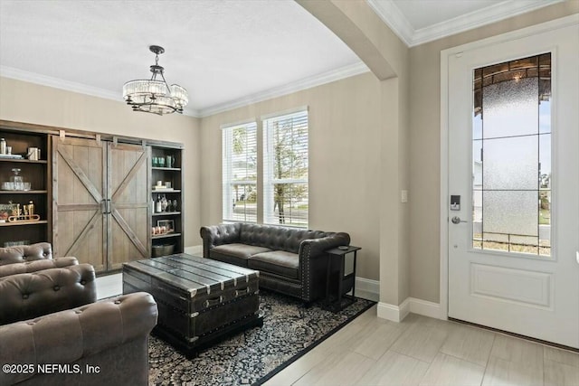 living room featuring arched walkways, a barn door, crown molding, baseboards, and an inviting chandelier