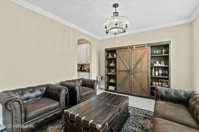 living area featuring arched walkways, a chandelier, a barn door, wood finished floors, and crown molding