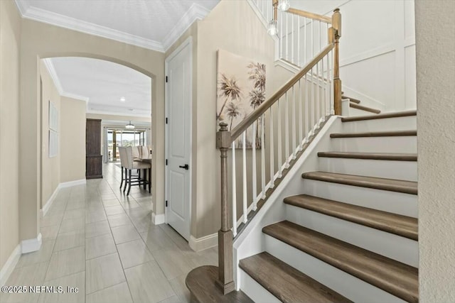 stairs featuring ornamental molding, arched walkways, baseboards, and tile patterned floors