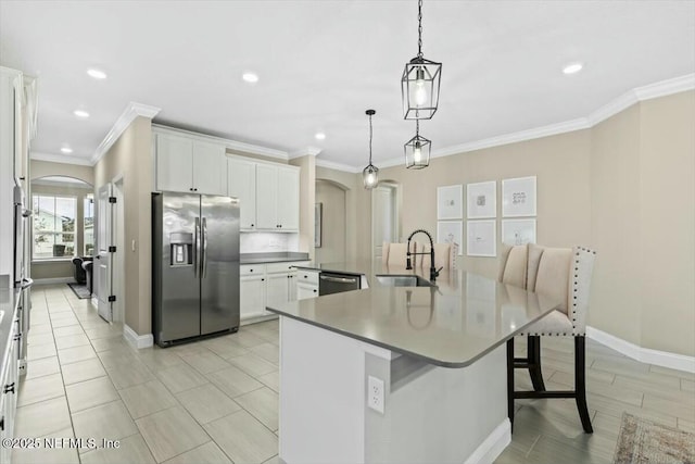 kitchen featuring arched walkways, white cabinets, appliances with stainless steel finishes, a kitchen bar, and a sink