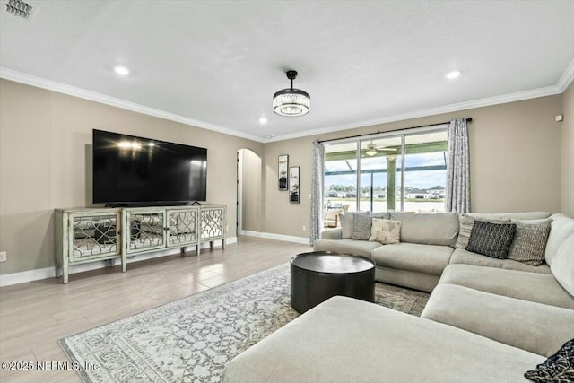 living area with baseboards, visible vents, arched walkways, and ornamental molding