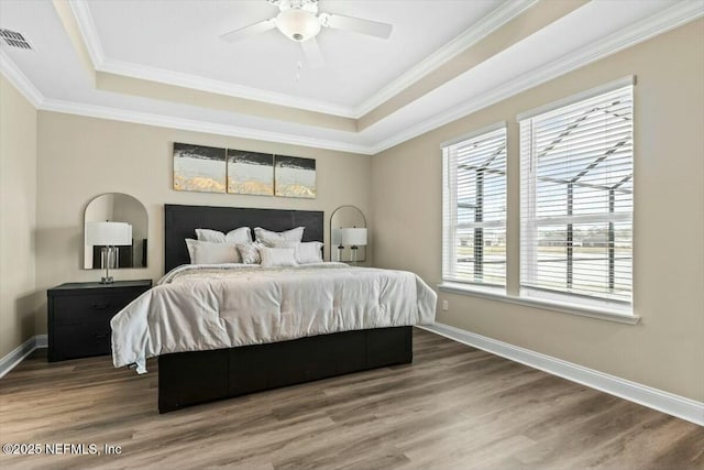 bedroom featuring a tray ceiling, wood finished floors, and baseboards