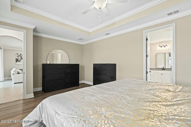 bedroom featuring arched walkways, wood finished floors, visible vents, baseboards, and crown molding