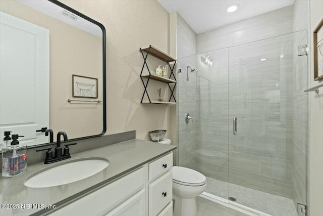 full bathroom featuring toilet, a stall shower, visible vents, and vanity