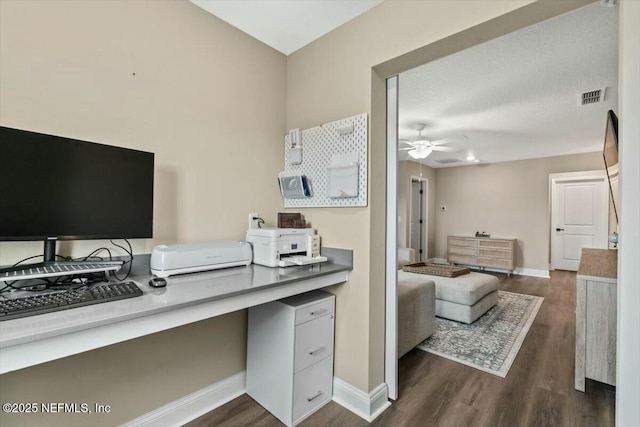 home office featuring baseboards, visible vents, dark wood finished floors, and a ceiling fan