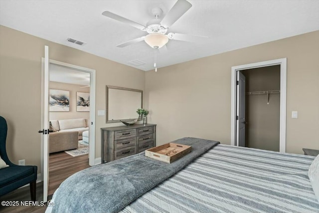 bedroom with ceiling fan, wood finished floors, visible vents, baseboards, and a closet