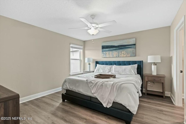 bedroom with ceiling fan, a textured ceiling, baseboards, and wood finished floors