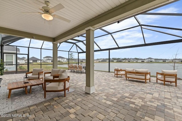 view of patio / terrace featuring outdoor dining area, a lanai, outdoor lounge area, a water view, and a ceiling fan