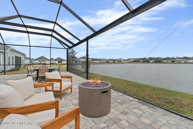 view of patio / terrace featuring a residential view, glass enclosure, an outdoor living space with a fire pit, and a water view