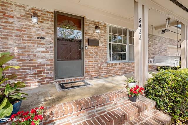 property entrance featuring covered porch and brick siding