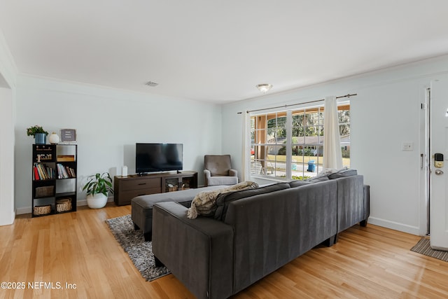 living area featuring light wood finished floors, visible vents, and baseboards