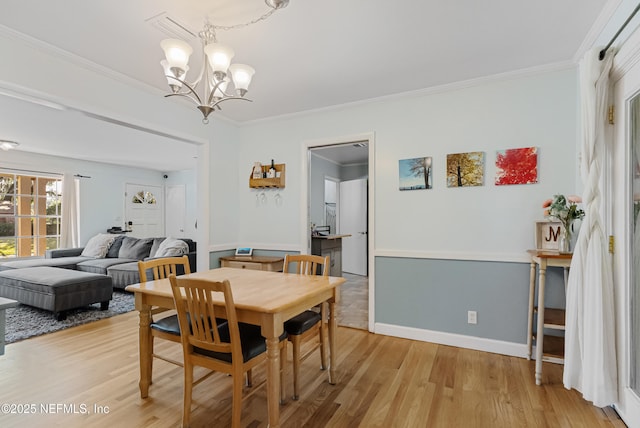 dining room with light wood-style floors, a chandelier, crown molding, and baseboards