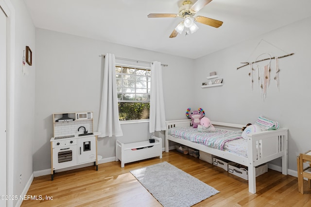 bedroom with ceiling fan, light wood finished floors, and baseboards