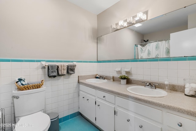 bathroom featuring double vanity, a sink, toilet, and tile walls