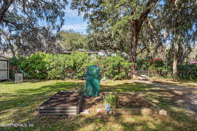 view of yard featuring a garden, fence, and an outbuilding