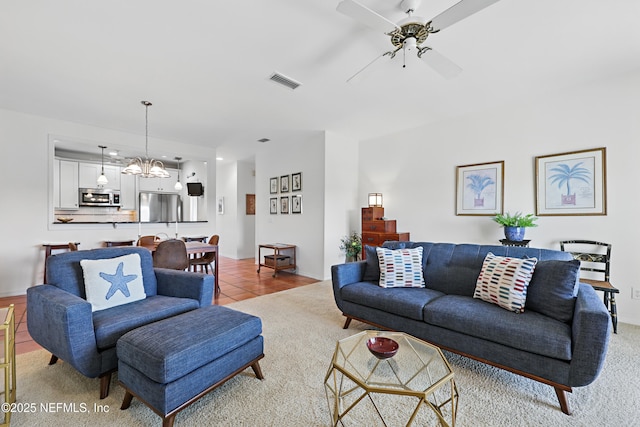 living room featuring light colored carpet, ceiling fan with notable chandelier, visible vents, and light tile patterned floors