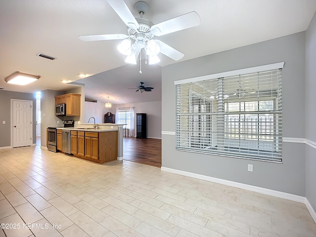 kitchen featuring a sink, stainless steel microwave, open floor plan, light countertops, and stove