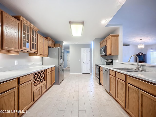 kitchen featuring a sink, glass insert cabinets, appliances with stainless steel finishes, and light countertops