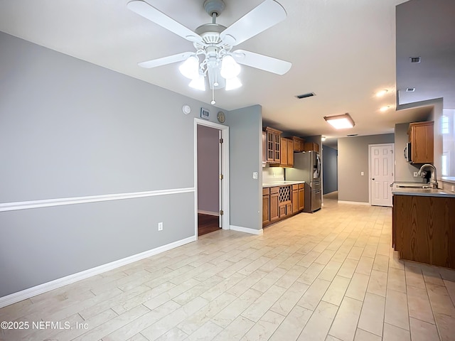 kitchen featuring a sink, visible vents, brown cabinets, and baseboards