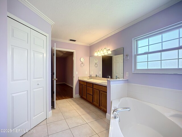 bathroom with crown molding, double vanity, a bath, a textured ceiling, and a sink