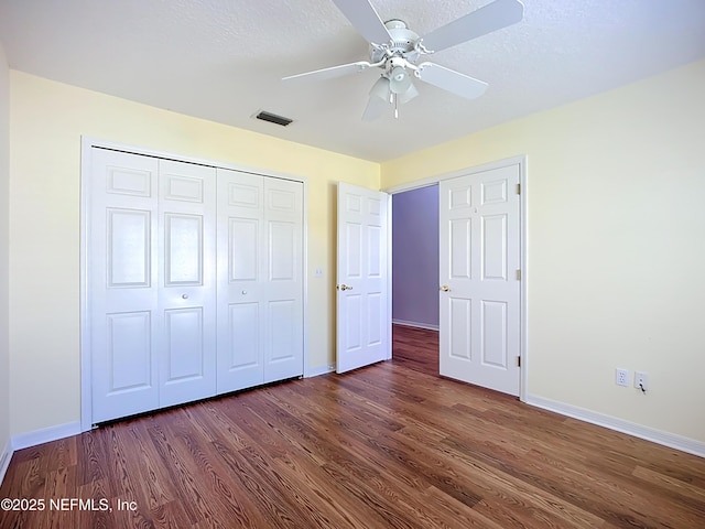 unfurnished bedroom with visible vents, baseboards, dark wood-type flooring, and a closet