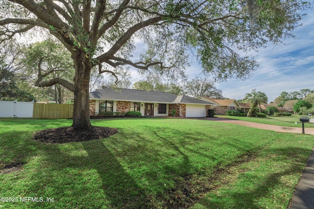 single story home featuring driveway, an attached garage, fence, a front yard, and brick siding