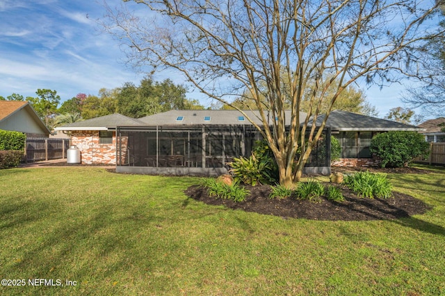 rear view of house with a sunroom, fence, a lawn, and brick siding