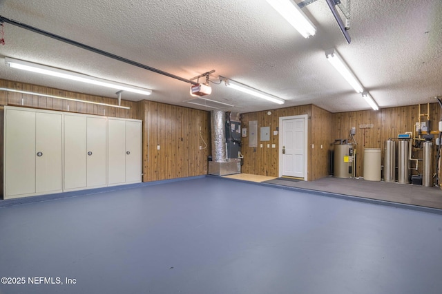 garage with a garage door opener, electric water heater, wood walls, and heating unit