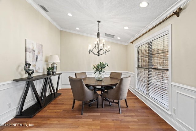 dining room with visible vents, wood finished floors, and wainscoting