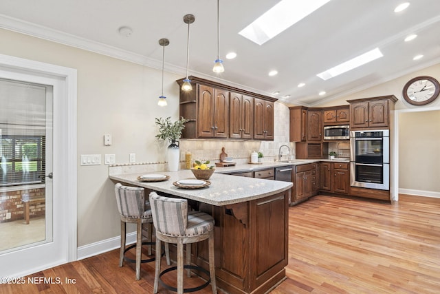 kitchen with stainless steel appliances, backsplash, ornamental molding, a peninsula, and a kitchen breakfast bar