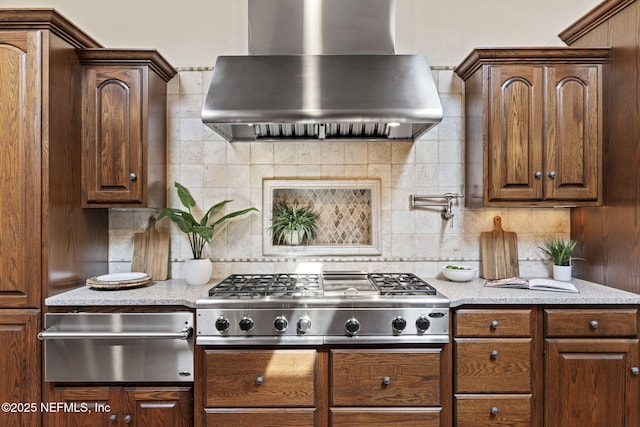 kitchen featuring a warming drawer, wall chimney exhaust hood, backsplash, and stainless steel gas stovetop