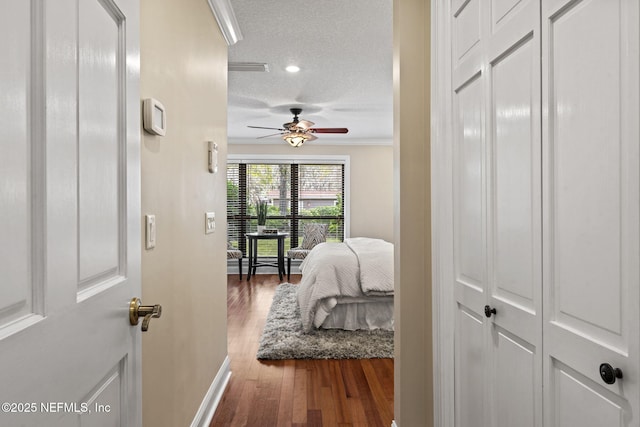 hall with baseboards, ornamental molding, a textured ceiling, and wood finished floors