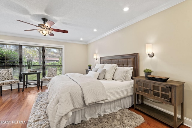 bedroom with baseboards, wood finished floors, crown molding, a textured ceiling, and recessed lighting