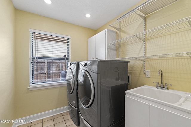 washroom with light tile patterned floors, cabinet space, a sink, washer and dryer, and baseboards